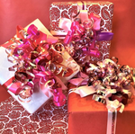 Three red and pink valentines day gift wrapped boxes with curly bows ribbons and wrapping paper