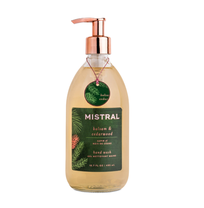 A glass bottle of Mistral hand wash with balsam and cedarwood scent, featuring a copper pump dispenser and a dark green label, shown on a white background.