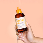 Hand holding a bottle of castor oil with a dropper showcasing the oil consistency