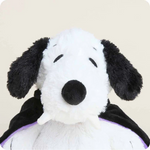 Plush toy resembling a black and white dog with a purple cape on a beige background