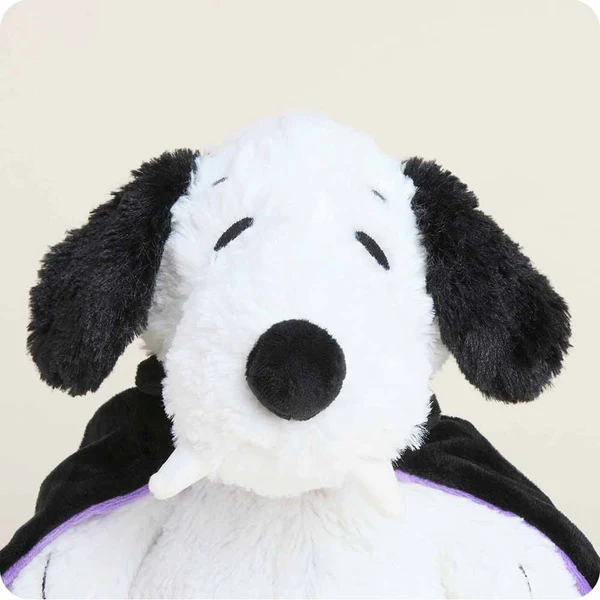 Plush toy resembling a black and white dog with a purple cape on a beige background