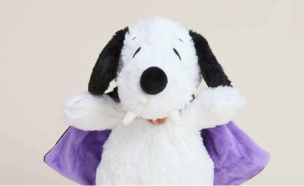 Plush Snoopy toy with a purple cape on a beige background