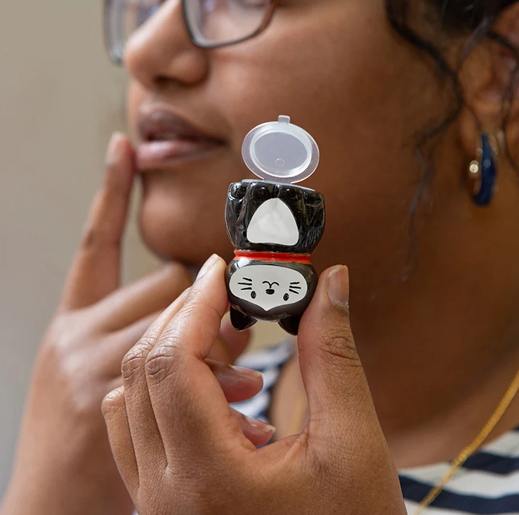 tuxedo cat lip balm application using a finger