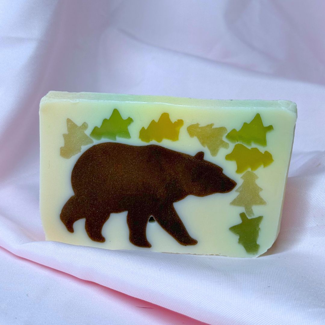 Bar of vegetable glycerin soap with a bear and tree design on a white background woodsy outdoors hiking camping summer