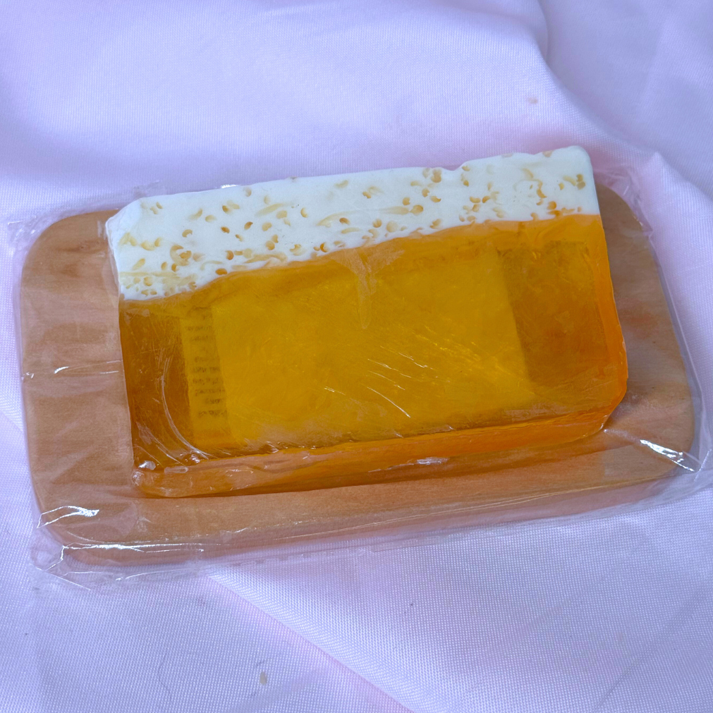 Yellow IPA beer alcohol soap bar with white top foam on a wooden soap dish, on a white background