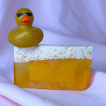 Yellow IPA beer alcohol soap bar with white top foam, gold glitter rubber duck with sunglasses on top of it, on a white background