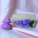 Bright purple lilac bar soap body wash soap and purple platypus duck cute gift set on pink fabric backdrop
