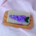 Bright purple lilac bar soap body wash soap on wooden soap dish cute gift set on pink fabric backdrop