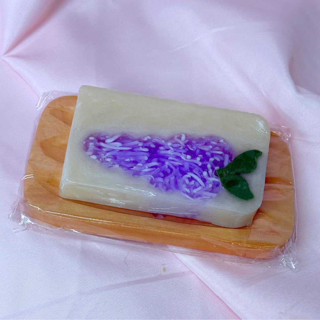 Bright purple lilac bar soap body wash soap on wooden soap dish cute gift set on pink fabric backdrop