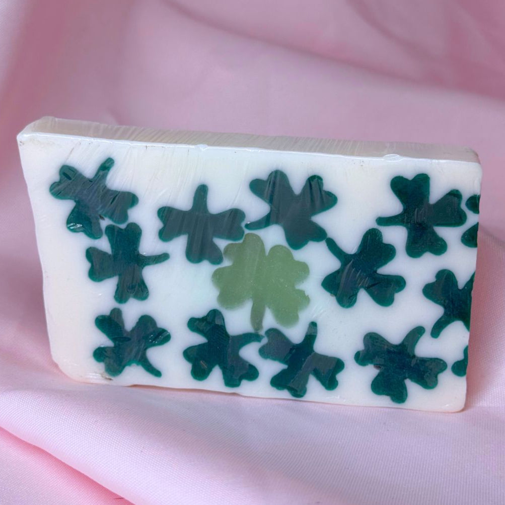 Luck of the irish saint patrick's St. Patrick's day bar soap with green clovers four leaf clovers and a pink fabric backdrop