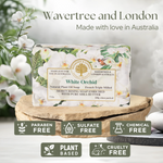 A bar of Wavertree and London White Orchid soap displayed on a wooden slice pedestal, with white orchid flowers and green leaves in the background. Text at the top reads 'Wavertree and London Made with love in Australia', and feature badges at the bottom highlight 'Paraben Free', 'Sulfate Free', 'Chemical Free', 'Plant Based', and 'Cruelty Free'.